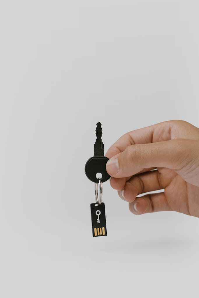 Close-up of a hand holding a key and USB representing document security.